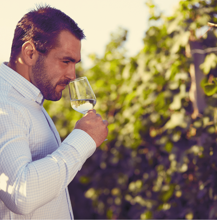 Winemaker tasting white wine in vineyard at sunny day  Toned